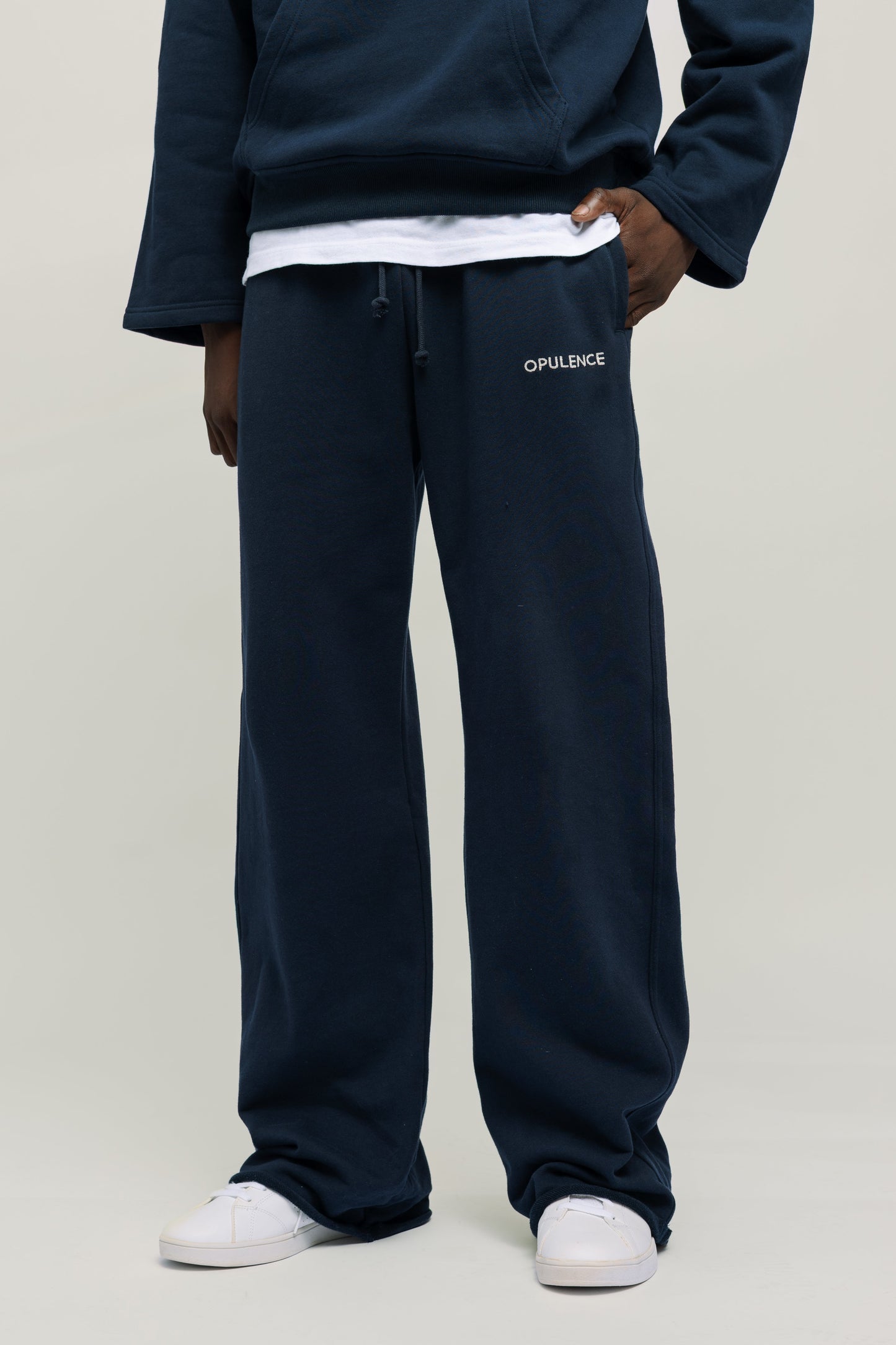 Person wearing navy blue sweatpants with brand logo on a light gray background