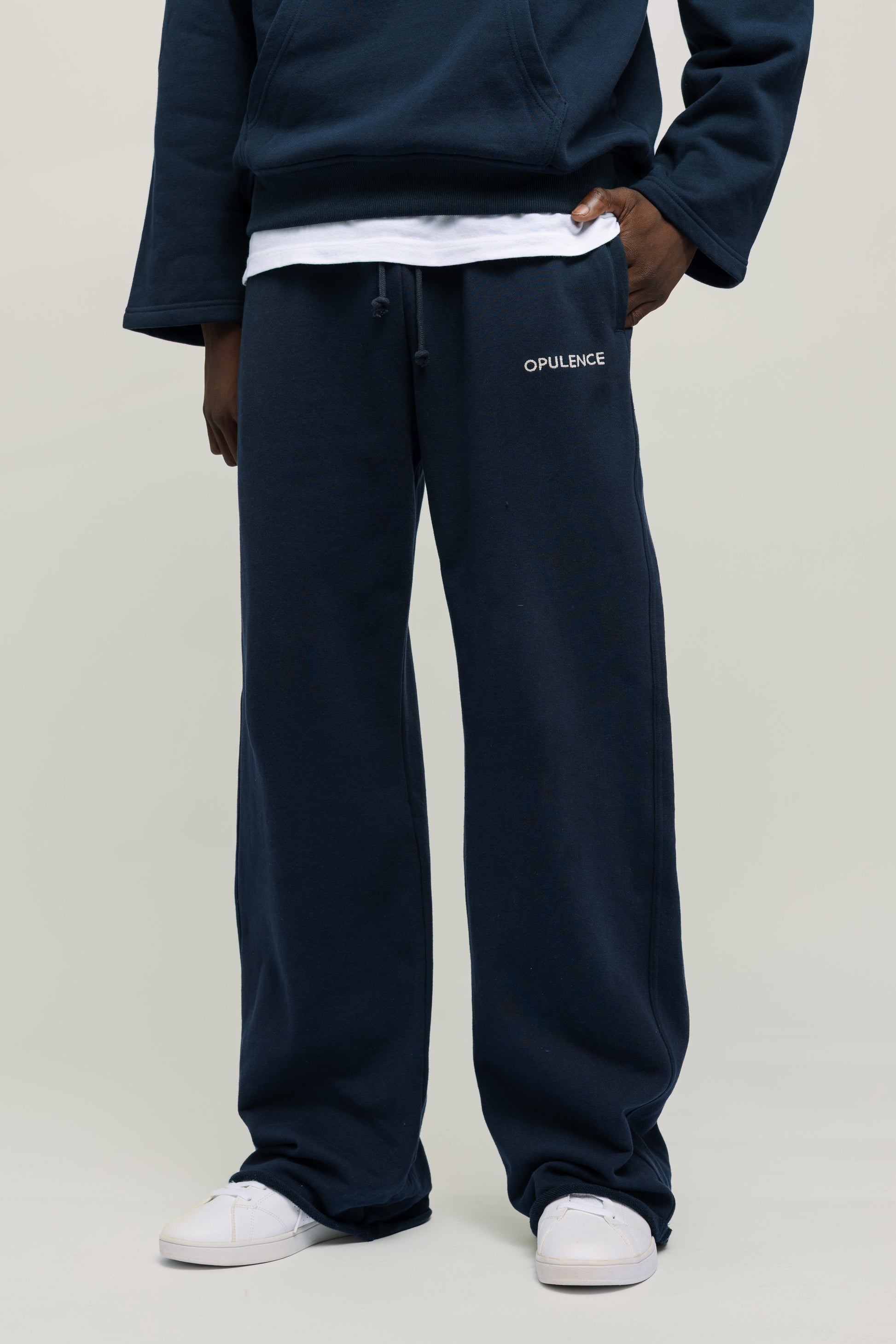 Person wearing navy blue sweatpants with brand logo on a light gray background